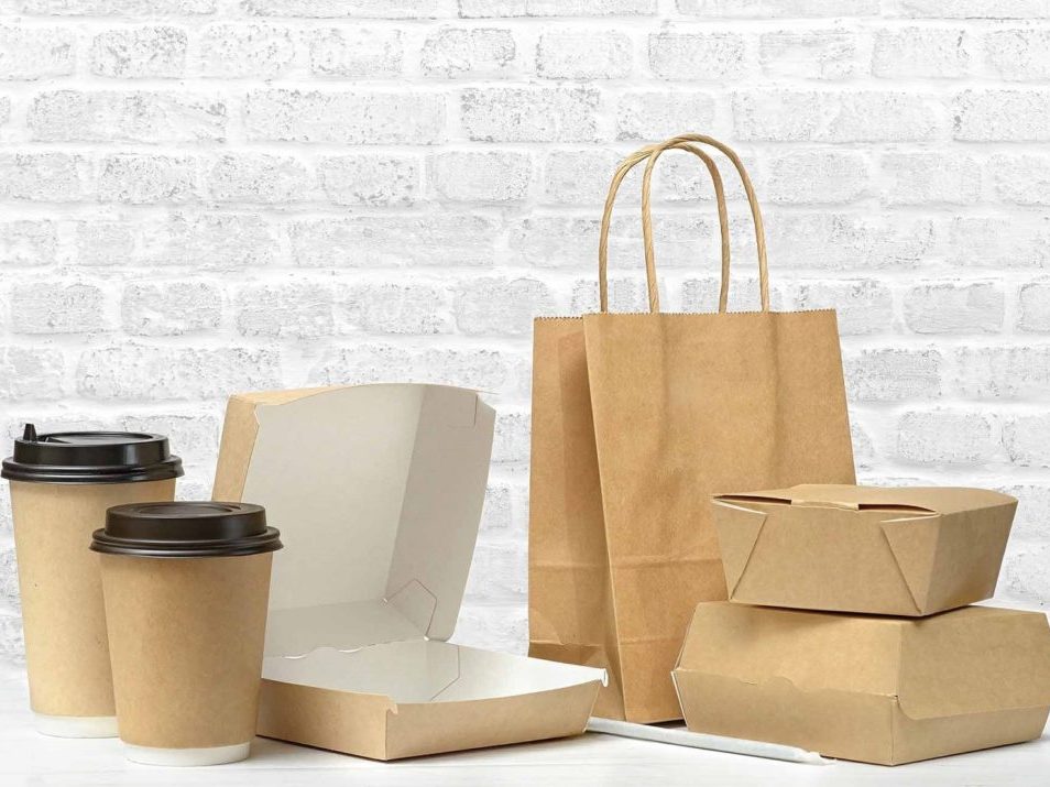 Fast food packaging set. Empty open food box, paper coffee cups, brown paper bag on the table on white brick wall background